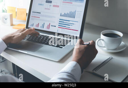 Young businessman typing computer laptop with graph chart for work Stock Photo