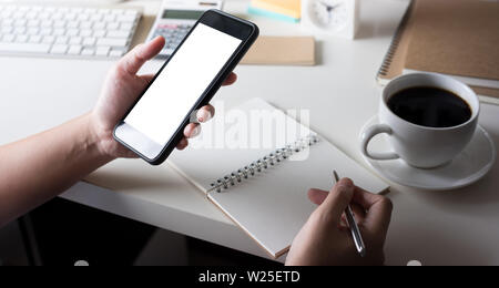Young woman using (touch screen) smartphone for work with worktable Stock Photo