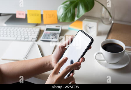 Young woman using (touch screen) smartphone for work with worktable Stock Photo