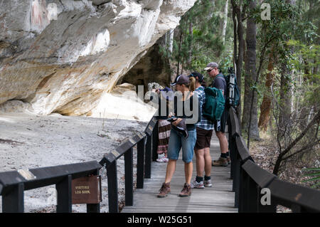 Visitors at the well preserved Aboriginal rock stencil art site, known as the ‘Art Gallery’ believed to be 3,650 years old on the white sandstone rock Stock Photo