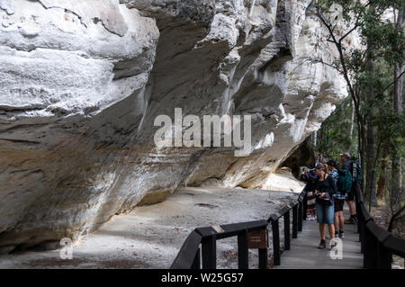 Visitors at the well preserved Aboriginal rock stencil art site, known as the ‘Art Gallery’ believed to be 3,650 years old on the white sandstone rock Stock Photo