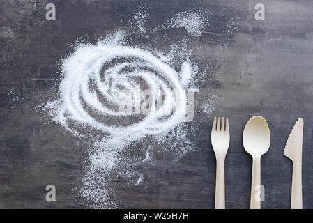 Top view of scattered sugar and fork, spoon, knife from wood. All on background of marble kitchen counter. Stock Photo
