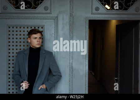 Elegant man in black turtleneck and melange grey blazer, standing next to  big wooden door Stock Photo - Alamy