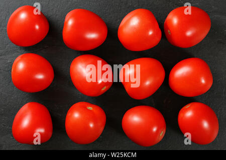 Top down view, dozen of mini tomatoes arranged on black stone desk Stock Photo