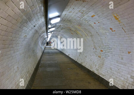 Wide angle photo of Greenwich foot tunnel under river Thames, people walking away in distance Stock Photo