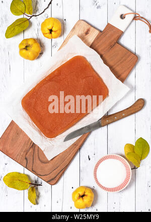 Traditional homemade quince block jelly on a wooden board with knife. Top view. Stock Photo