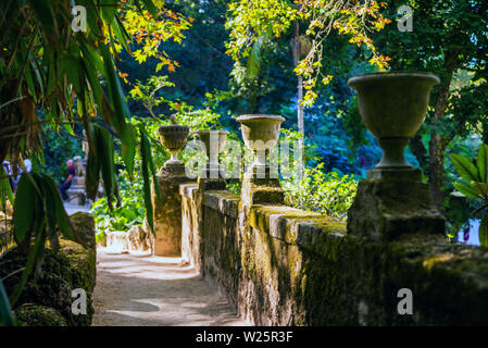 Garden decorative decoration among the greenery, an ancient granite vase stands on a pedestal in the Park. Stock Photo