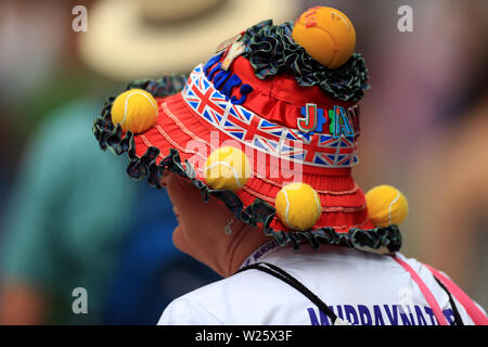 A spectator wearing a tennis themed hat on day six of the Wimbledon Championships at the All England Lawn Tennis and Croquet Club, Wimbledon. Stock Photo