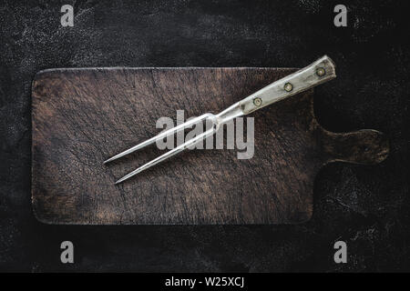 Old Fork and Rustic Cutting Board on Dark Background Stock Photo