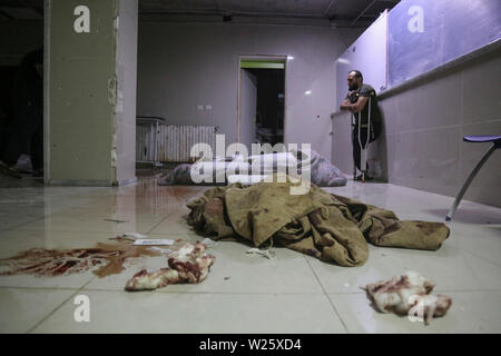 Muhambal, Syria. 06th July, 2019. A man stands next to the bodies of dead people lying under blocks of ice at a makeshift morgue, after they were killed the day before in an airstrike allegedly carried out by the Syrian government on the town of Muhambal in the rebel-held Idlib Province. Credit: Anas Alkharboutli/dpa/Alamy Live News Stock Photo