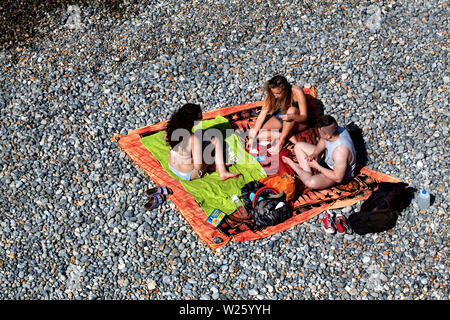 Three people playing cards on Sherringham beach, Norflk. Stock Photo