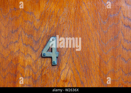 House number 4 with the four in metal digits on a wooden front door with natural grain Stock Photo