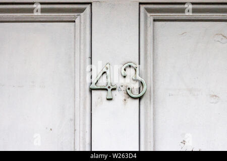 House number 43 with the forty-three in crooked metal digits on a white wooden front door Stock Photo