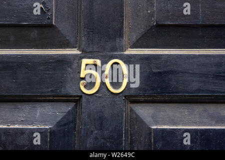House number 50 with the fifty in metal digits on a wooden front door Stock Photo