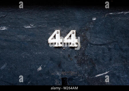 House number 44 with the forty-four  in silver metal digits on a wooden front door Stock Photo