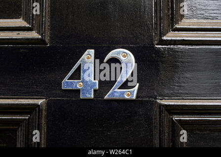 House number 42 with the forty-two in shiny silver metal digits on a black wooden front door