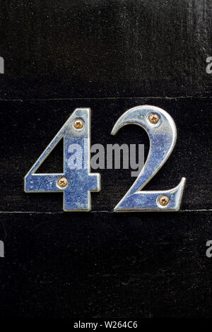 House number 42 with the forty-two in shiny silver metal digits on a black wooden front door