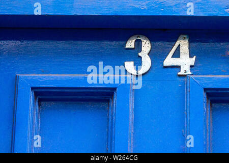 House number 34 with the thirty-four in metal digits on a blue wooden front door Stock Photo