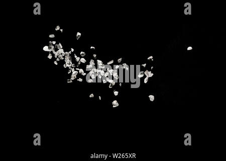 Split debris of stone exploding against black background. Stock Photo