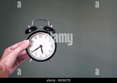 Hand holding an alarm clock, wake up or time concept Stock Photo