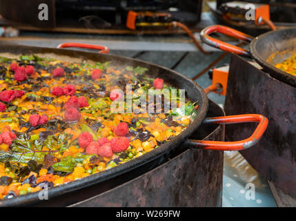 paella is cooking in a a big gas cooker and steam is bubbling Stock Photo