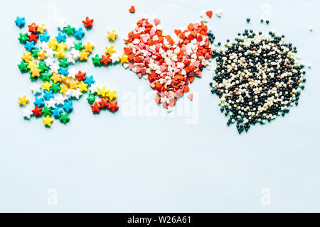 Three heaps of multi-colored dragee lollipops on a background top view. Summer sweet flat lay. Stock Photo