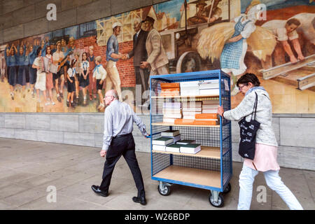 German officials pushing cart documents below socialist realism art from the time of the Communist German Republic Ministry of Finance, Berlin Germany Stock Photo