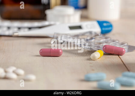 Blister pack, colored pills and medical thermometer on wooden table Stock Photo