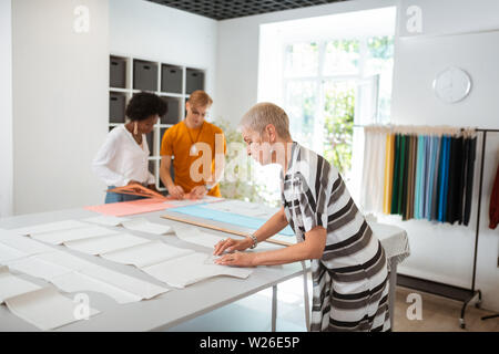 Serious task. Serious professional female fashion designer working on a new sewing pattern using a triangle Stock Photo