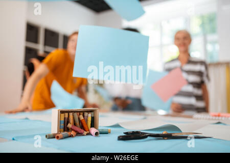 Sewing tools. Closeup of scissors, a box of colored threads and other sewing tools lying on the cutting table in a fashion designers studio Stock Photo