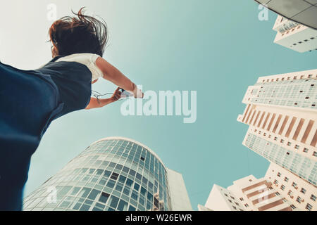 A girl is taking pictures of a new residential complex. White modern skyscrapers. New housing. Stock Photo