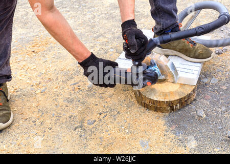 The worker uses a diamond cutting disc and an angle grinder to cut the paving bar and metal plate. Stock Photo