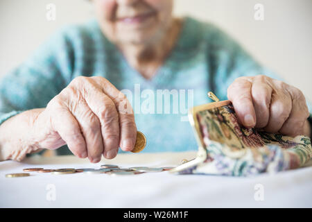 Detailed closeup photo of unrecognizable elderly womans hands counting remaining coins from pension in her wallet after paying bills. Stock Photo