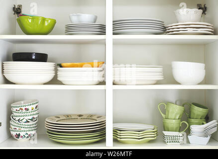 Tableware placed on a wooden shelf. Closeup of plates and dinnerware in a cupboard. Stock Photo