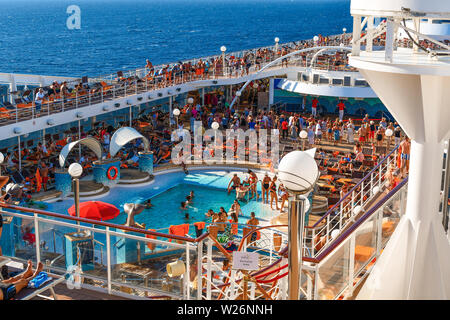 Athens, Greece - September 18 2018: Tourists lounge in the sun, swim and party on the upper deck of a large cruise ship Stock Photo