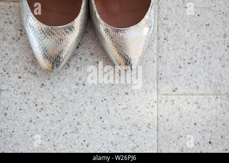 Closeup of the brides silver shoes toes on the marble floor Stock Photo