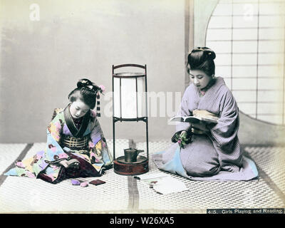 [ 1890s Japan - Japanese Women in Kimono ] —   Two women in kimono reading and playing. An andon lamps stands between them.  19th century vintage albumen photograph. Stock Photo