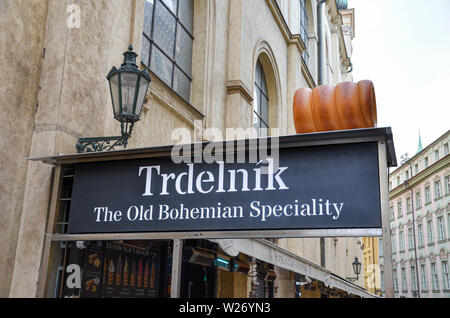 Prague, Czech Republic - June 27th 2019: Sign of street stand selling trdelnik - traditional Czech dessert and popular Bohemian dish. Tasty cake, bakery. Sweet roll with filling. Stock Photo