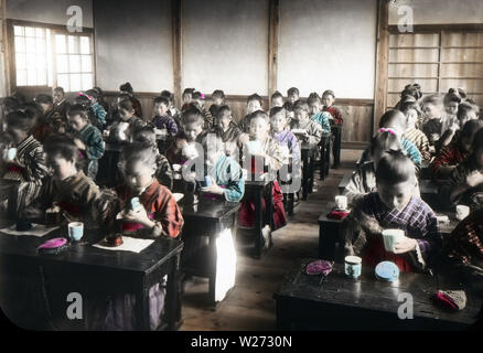 [ 1900s Japan - Female Elementary School Students ] —   Japanese elementary school students eating in a classroom.  This image is part of 'The School Life of Young Japan' (No 9), a series published by Japanese photographer Kozaburo Tamamura in the early 1900s (late Meiji).  20th century vintage glass slide. Stock Photo