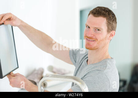 repairman putting picture frame onto wall Stock Photo