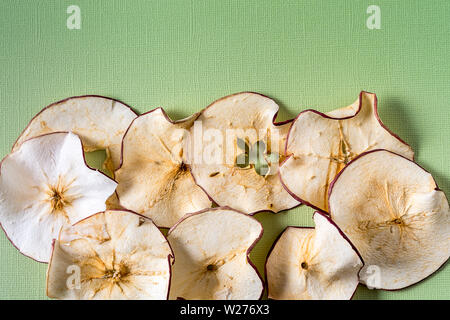 Flat lay Baked Dehydrated dried Apples Chips over green background with copy space. Stock Photo
