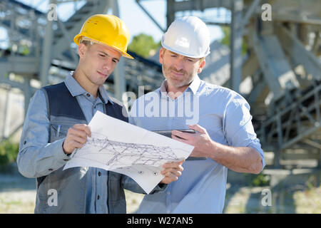 two engineers looking at plans for new building Stock Photo
