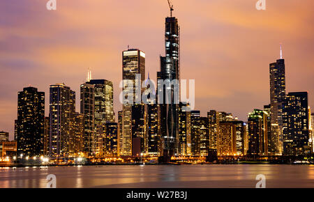 Chicago Illinois skyline, sunset time. Panoramic view of Chicago city waterfront illuminated skyscrapers, cloudy sky in the evening