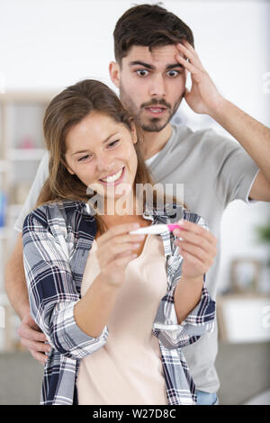 excited wife and not ready worried man with pregnancy test Stock Photo