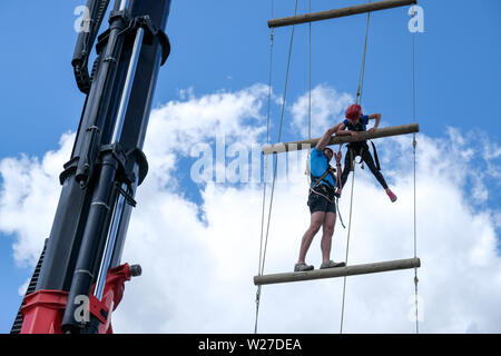 Dortmund/Germany, 19th June 2019. At the Protestant Church Congress 2019 in Dortmund, a girl (10 years) climbs up to a height of 17 meters on a ladder to heaven. A helper assists with ropes to reach the next level. Stock Photo