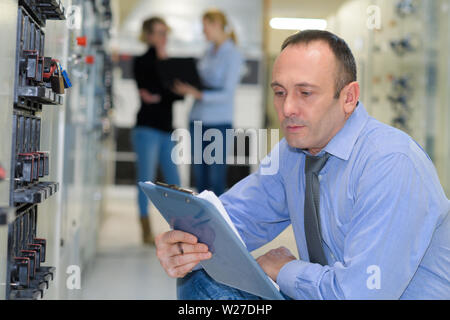 technician maintaining record of rack mounted server Stock Photo