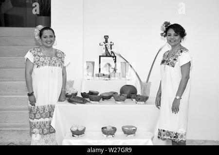 MERIDA, YUC/MEXICO - NOV 1ST, 2013: Hanal Pixan (Day of the Dead). Two women in traditional attire pose next to an altar. BW film Stock Photo