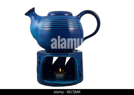 blue ceramic teapot with a candle heated on a white background Stock Photo