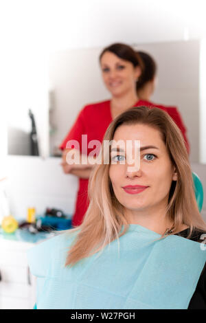 The dentist and her happy patient look at the camera and smile. Reception at the dentist, healthy teeth, happy patient, beautiful teeth. Stock Photo