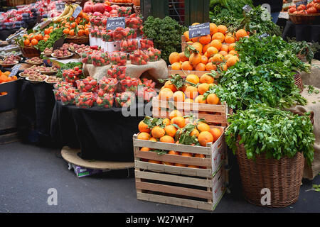 London, UK - February, 2019. Green groceries including oranges, strawberries and parsley on sale at a vegetables stall in Borough Market. Stock Photo
